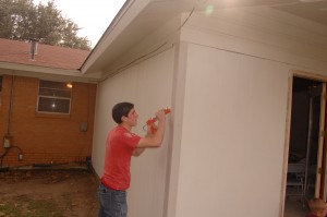 Aaron Courter caulks the new siding at the back of the house.